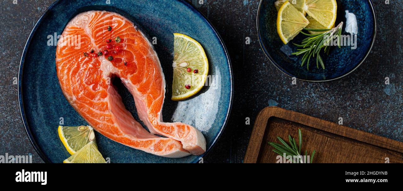 Steak de saumon cru au poisson frais vue de dessus sur l'assiette rustique en béton foncé sur fond de pierre Banque D'Images