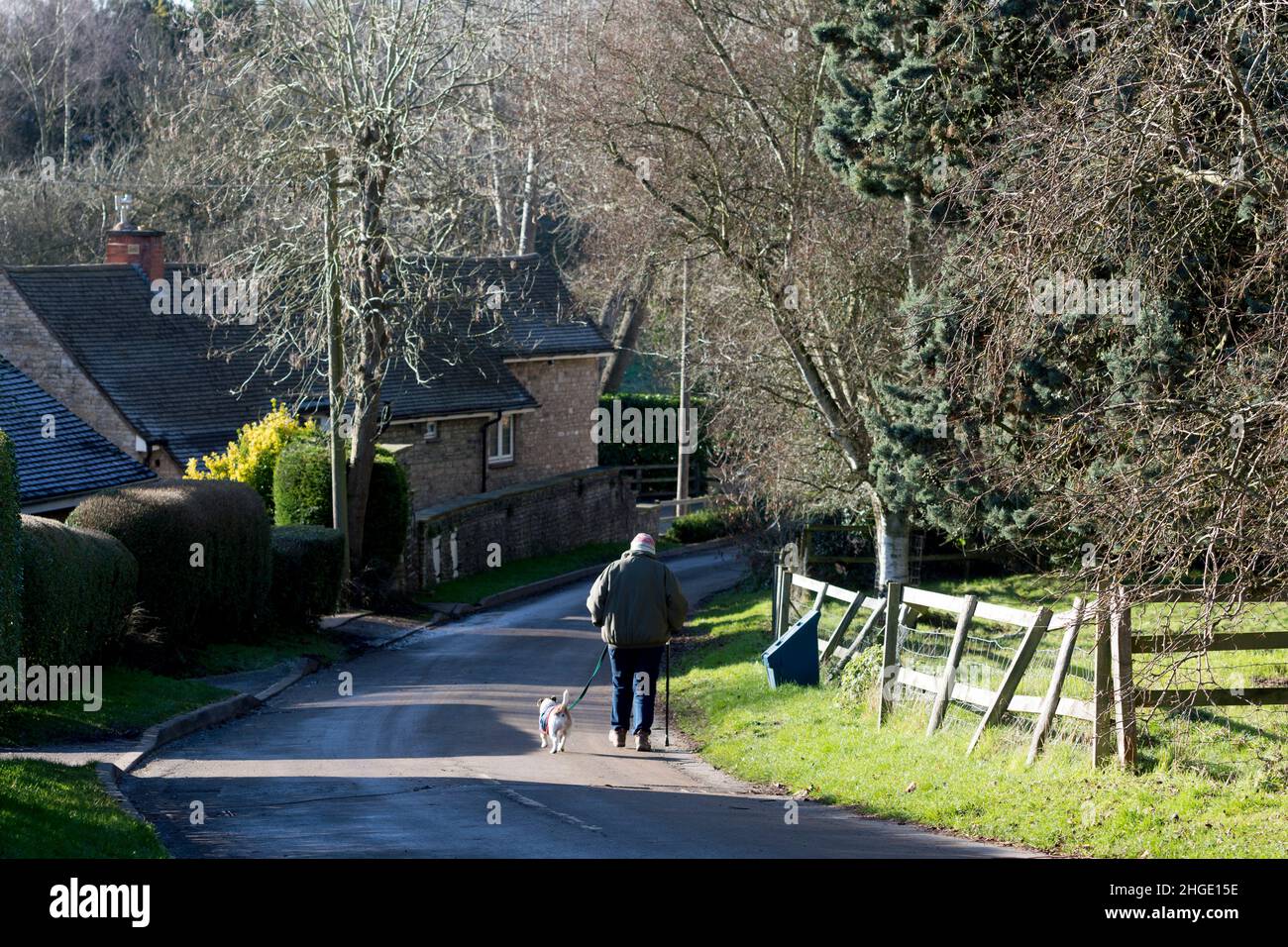 Personne marchant un chien dans le village de Lighthorne, Warwickshire, Angleterre, Royaume-Uni Banque D'Images