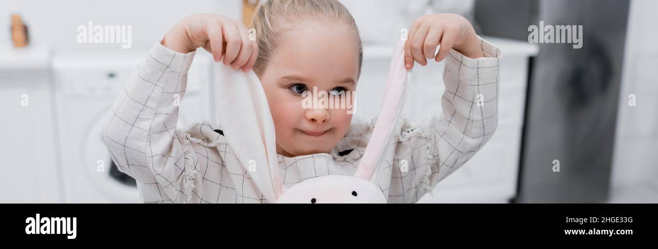 petite fille jouant avec le lapin jouet dans la cuisine, bannière Banque D'Images