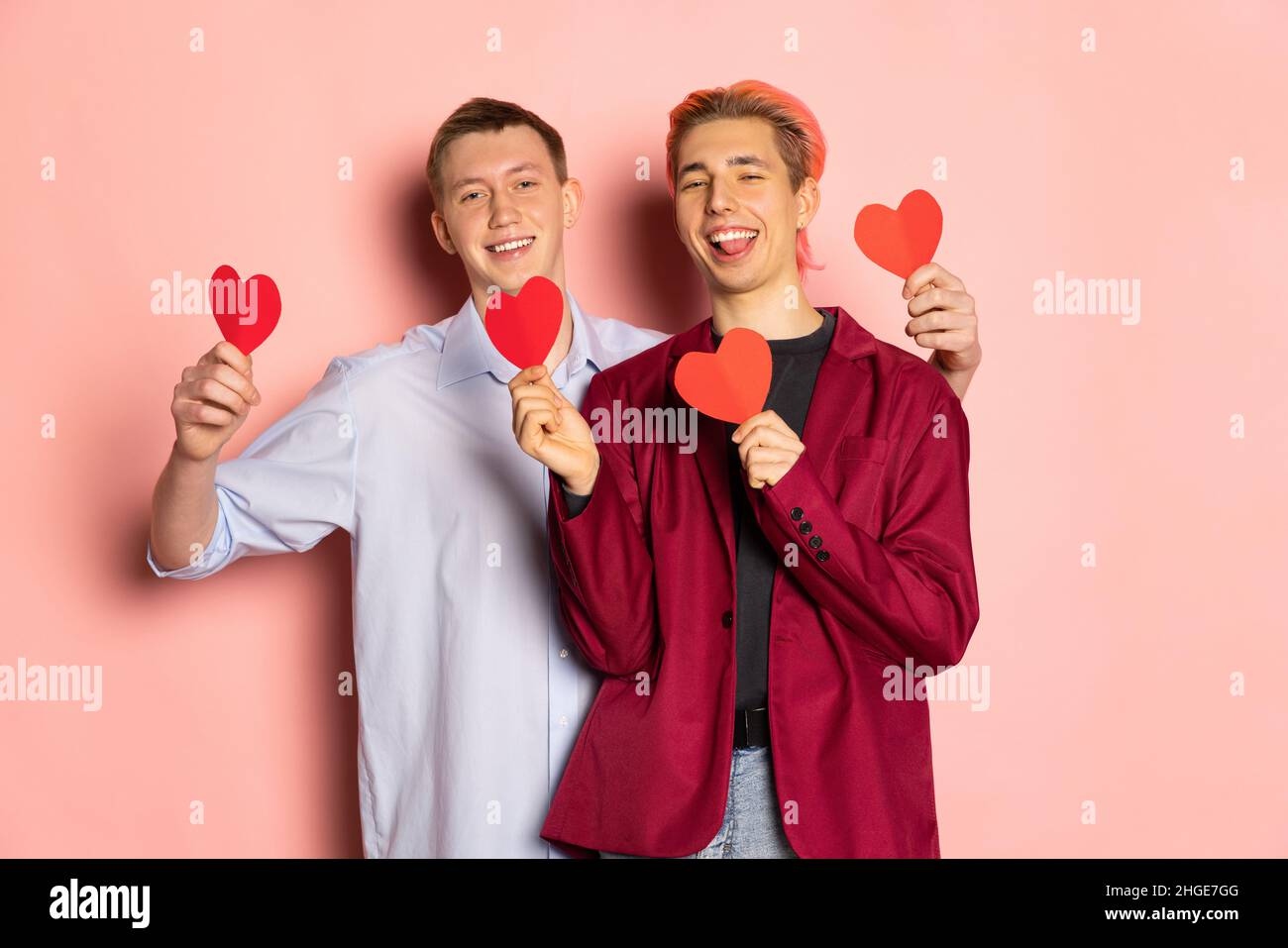 Des hommes heureux, un jeune couple tenant des cartes de voeux en forme de coeur.Célébration de la Saint-Valentin.Concept d'émotions, d'amour, de relations, de vacances romantiques. Banque D'Images