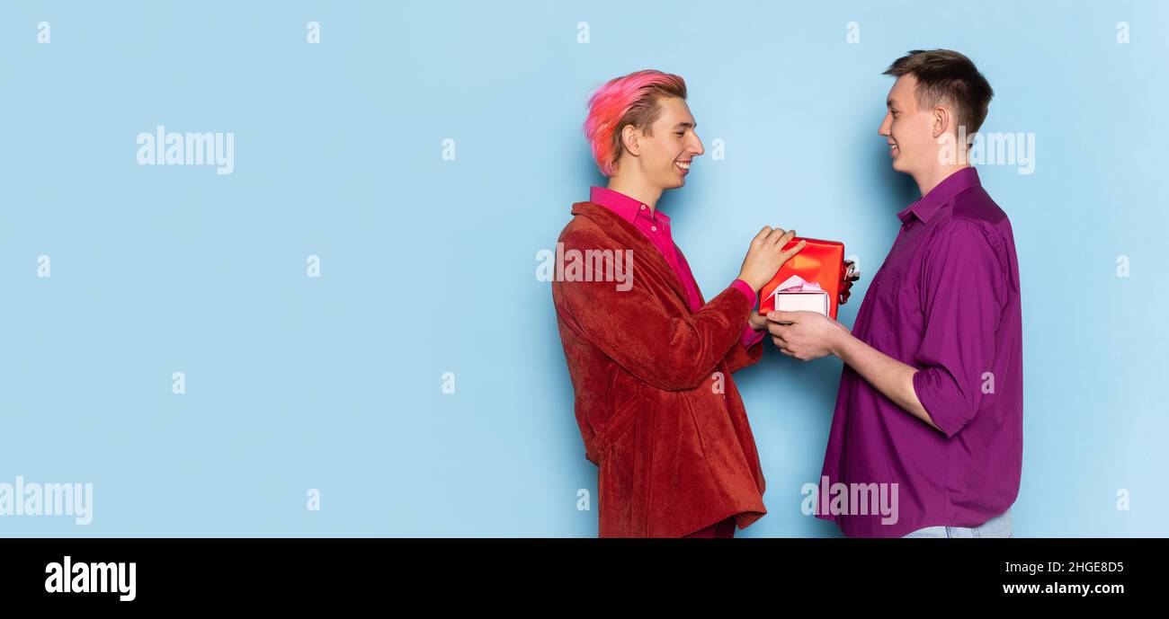 Portrait de jeunes hommes, couple posant isolé sur fond bleu.Célébration de la Saint-Valentin.Concept des émotions, de l'amour, des relations, romantique Banque D'Images