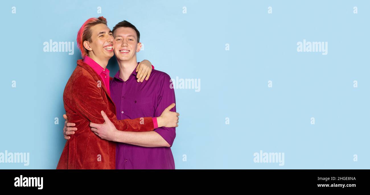 Portrait de jeunes hommes, couple posant isolé sur fond bleu.Concept d'émotions, d'amour, de relations, de romantisme, de diversité Banque D'Images