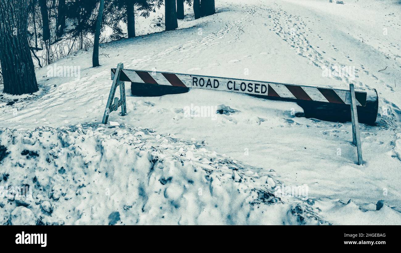 Route fermée à la route avec de la neige profonde après une chute de neige fraîche.Preuve de personnes qui marchent autour de l'affiche avec les empreintes de pas. Banque D'Images