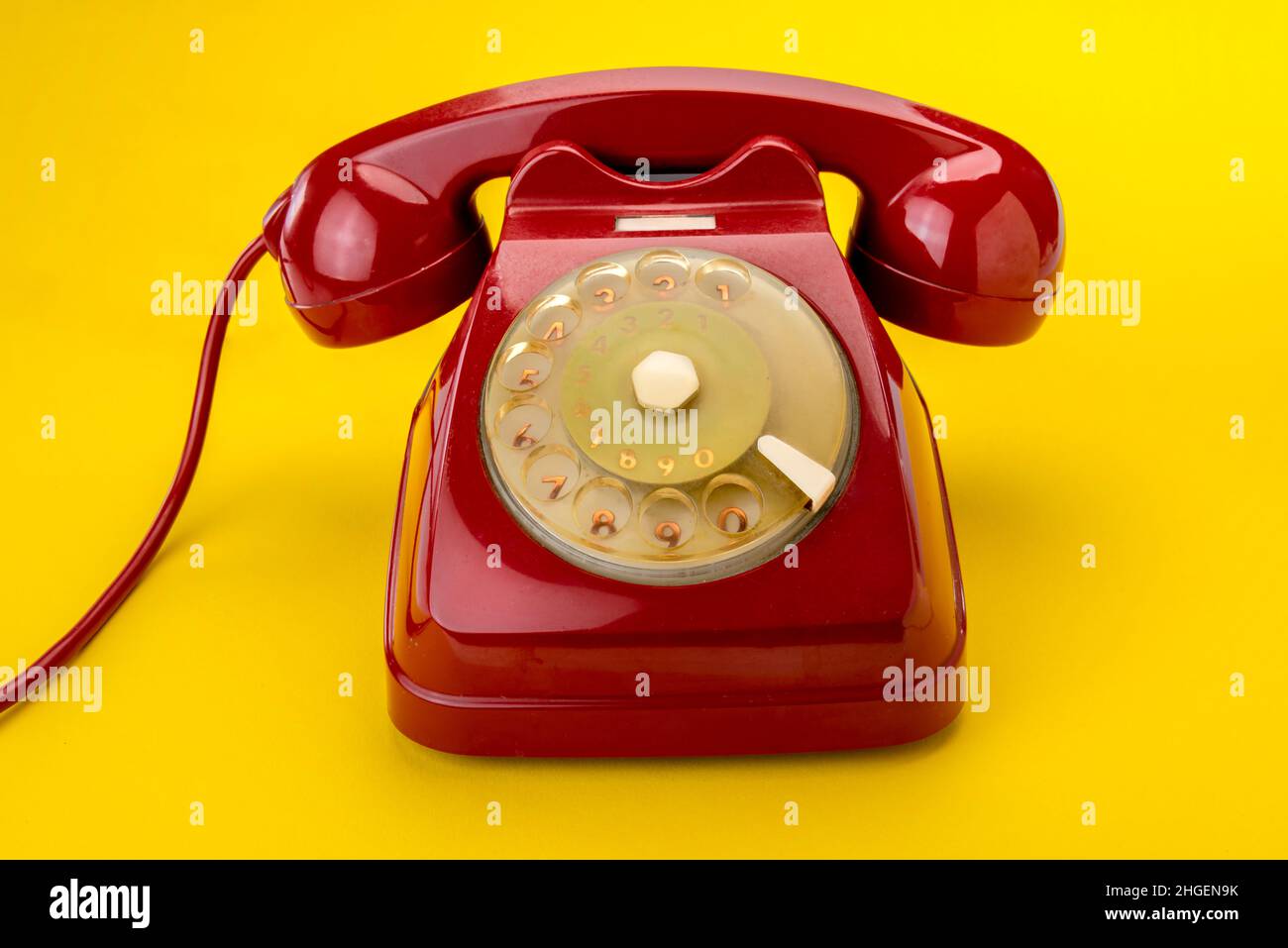 Vieux téléphon à cadran rotatif rouge isolé sur fond jaune Banque D'Images