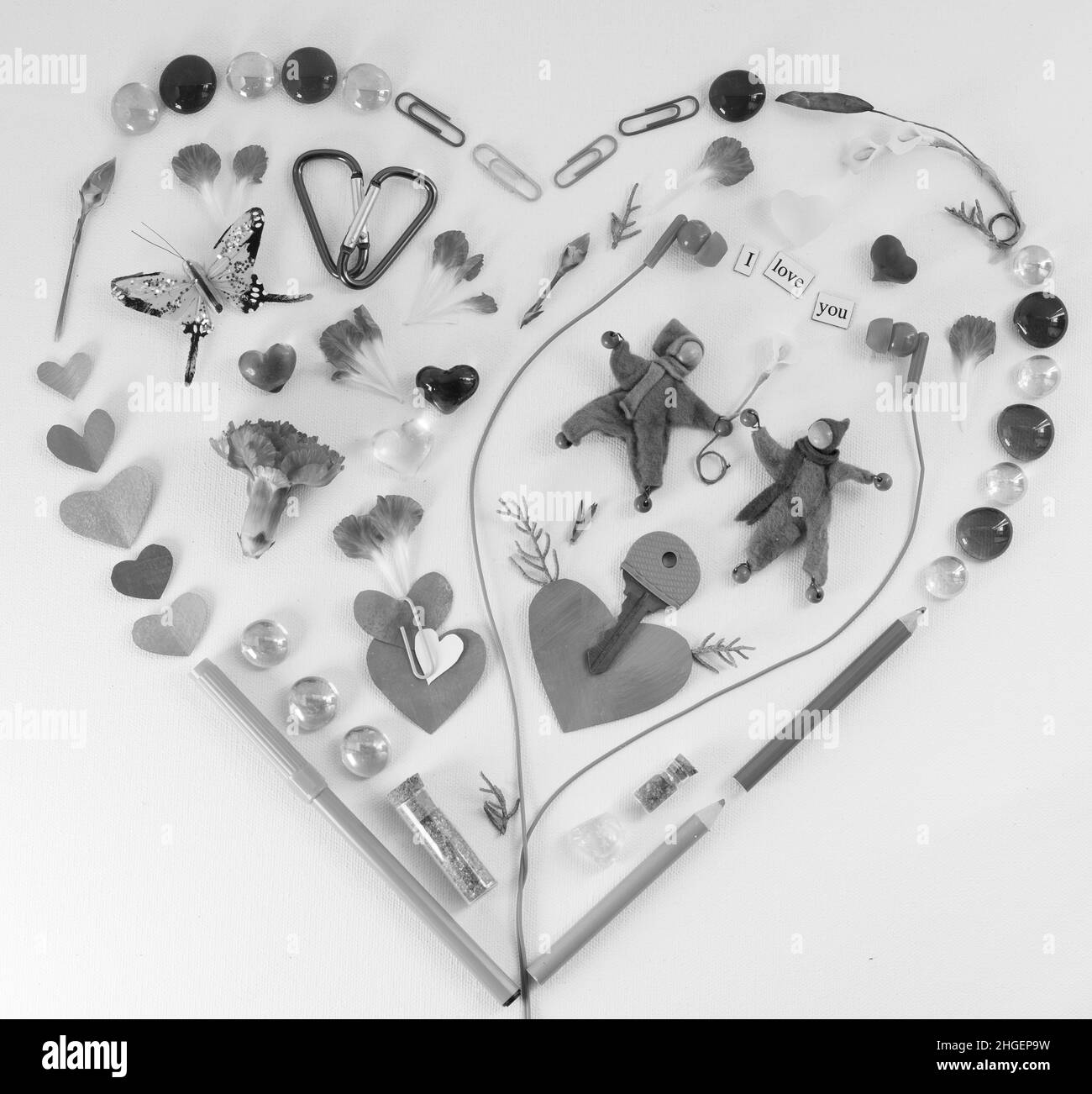 Motif lat en forme de coeur utilisant des fournitures de bureau et d'art, des pétales, papillon, tête de jeu et des caractères neutres de genre avec une clé, la carnation et découpé Banque D'Images