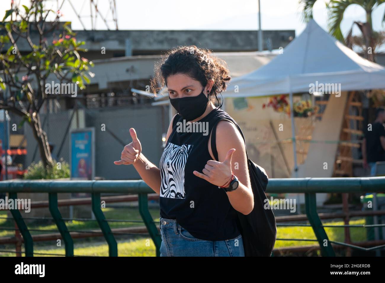 Medellin, Antioquia, Colombie - décembre 7 2021 : femme aux cheveux bouclés portant des vagues de masque noir avec ses mains Banque D'Images