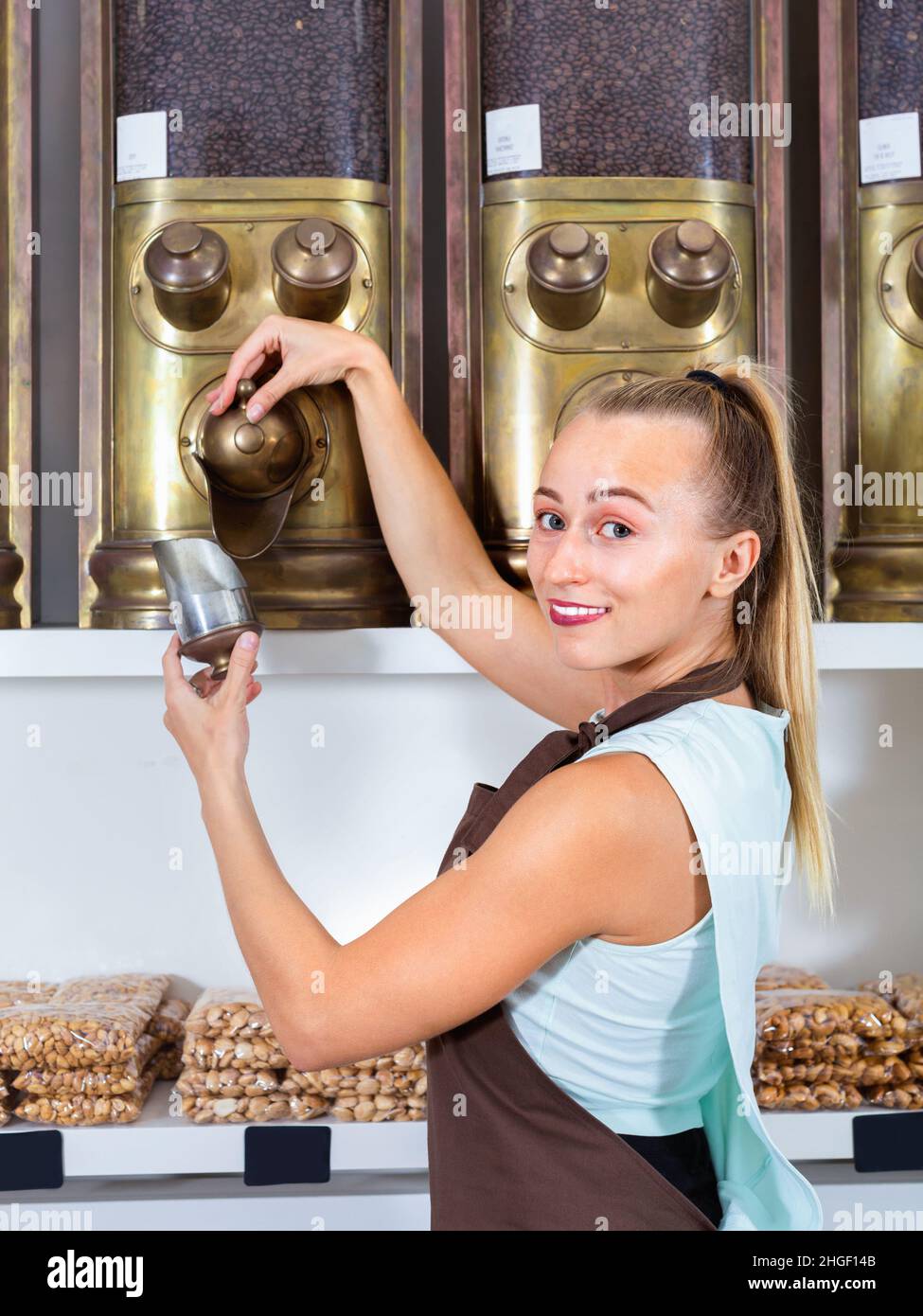 La femme vendeuse verse du café dans les récipients de la boutique alimentacion. Banque D'Images
