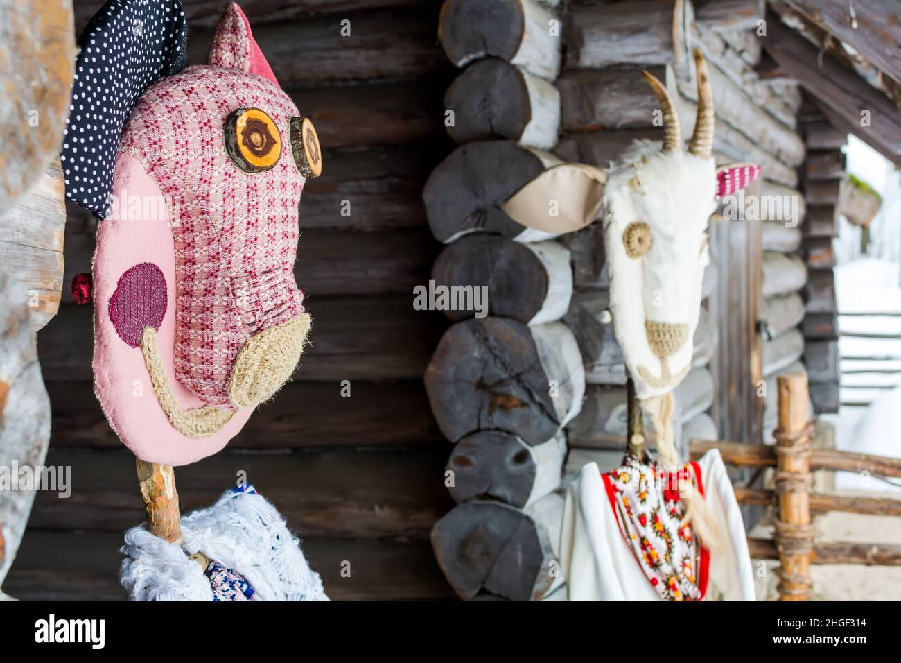 Poupées dans les masques de Meteņi et costumes de cochon et de chèvre debout à la maison de charrette de bois Banque D'Images