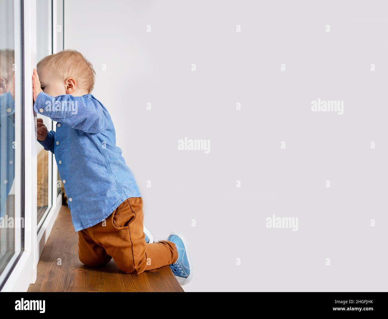 Enfant jouant dangereusement sur un seuil de fenêtre. Banque D'Images