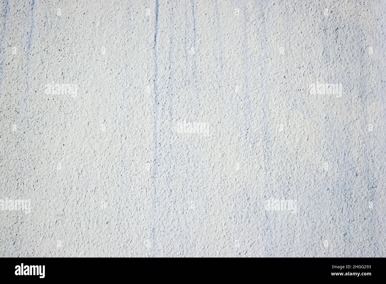 Mur léger et rugueux peint avec des taches de peinture bleue. Banque D'Images