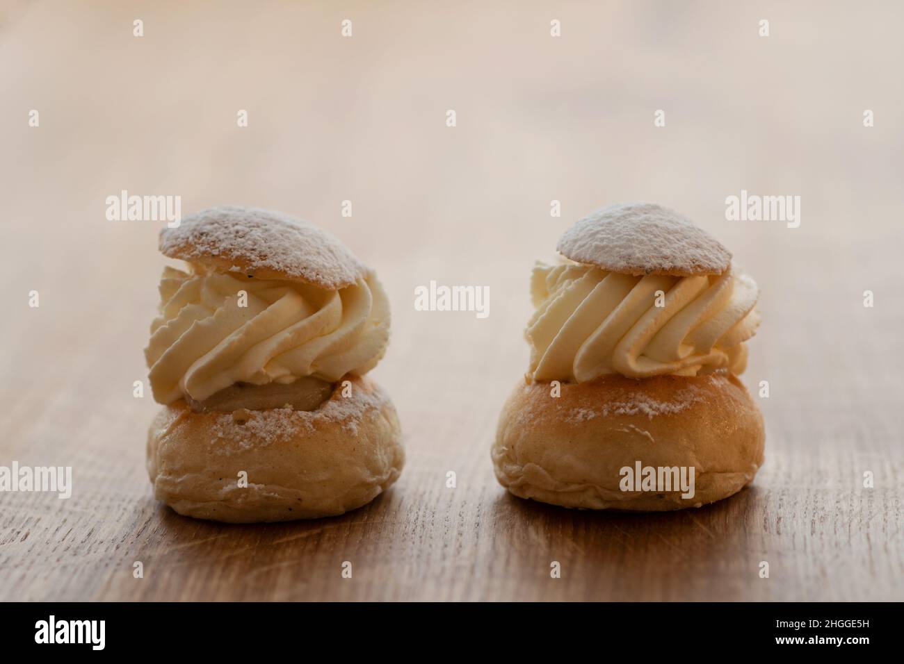 Deux morceaux de pâte suédoise traditionnelle, la semla, sur une table en bois.Petit pain à deux couches, farci de pâte d'amande sous une couverture de crème fouettée. Banque D'Images
