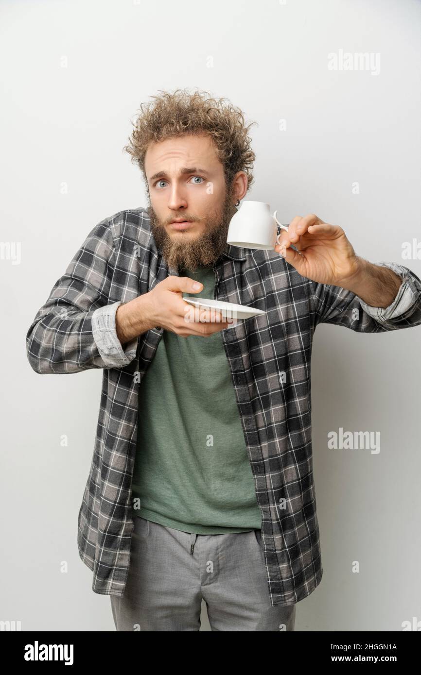 Jeune homme avec une tasse et une soucoupe inversées et vides dans ses mains.Concept de l'endroit où est mon café, à la dernière goutte.C'était la dernière paille de ma patience.Photo de haute qualité Banque D'Images