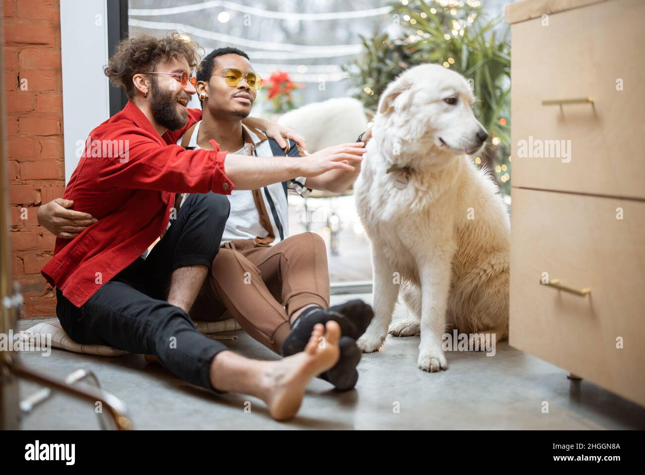 Deux gars s'occupent de chien tout en étant assis sur le sol à la maison Banque D'Images