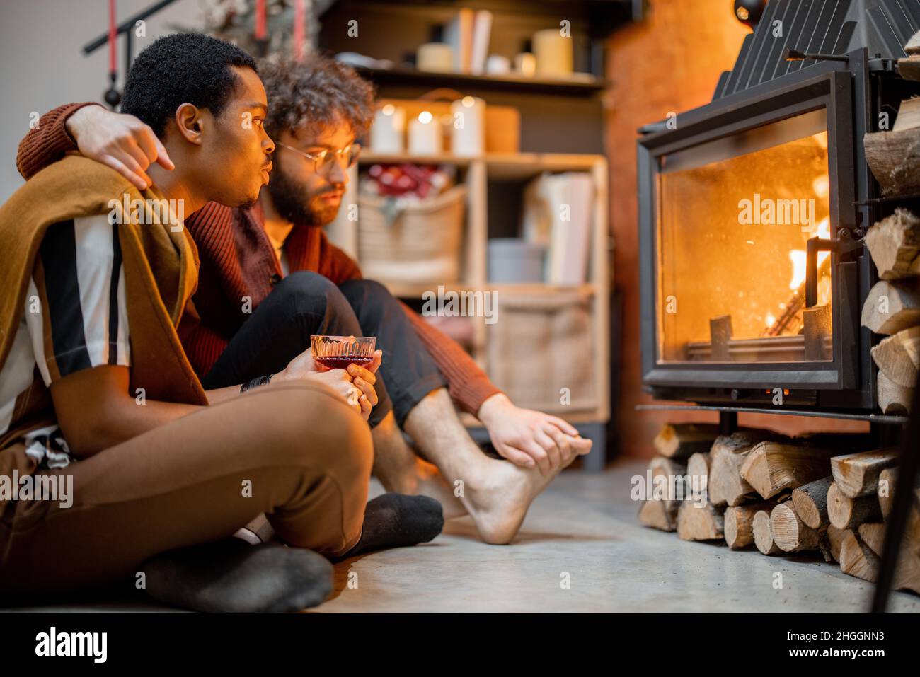Deux hommes assis ensemble près de la cheminée à la maison confortable Banque D'Images