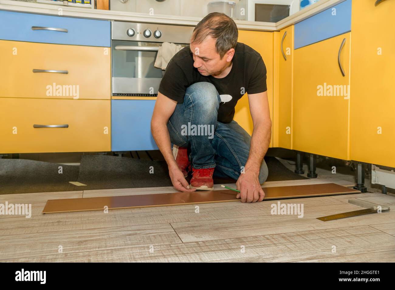 Homme travaillant avec des doigts amputés. Il travaille à poser le plancher dans sa maison pendant la journée. Banque D'Images