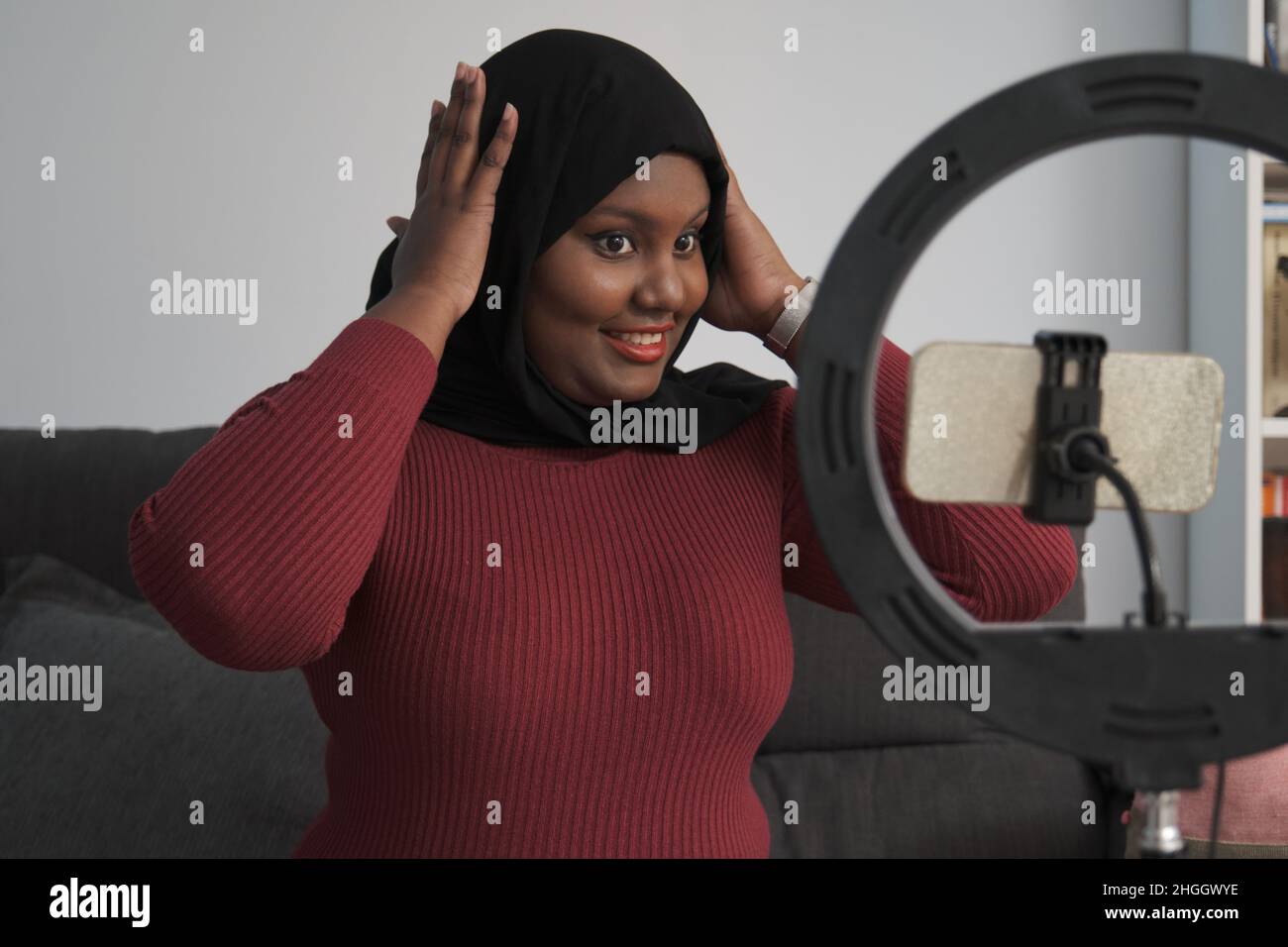 Une jeune femme musulmane heureuse enseignant comment réparer le hijab en ligne. Banque D'Images