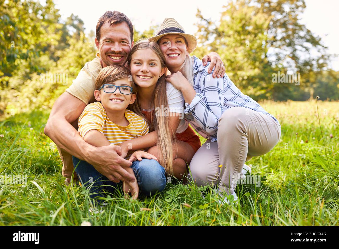 Une famille heureuse avec deux enfants se hale dans une prairie en été Banque D'Images