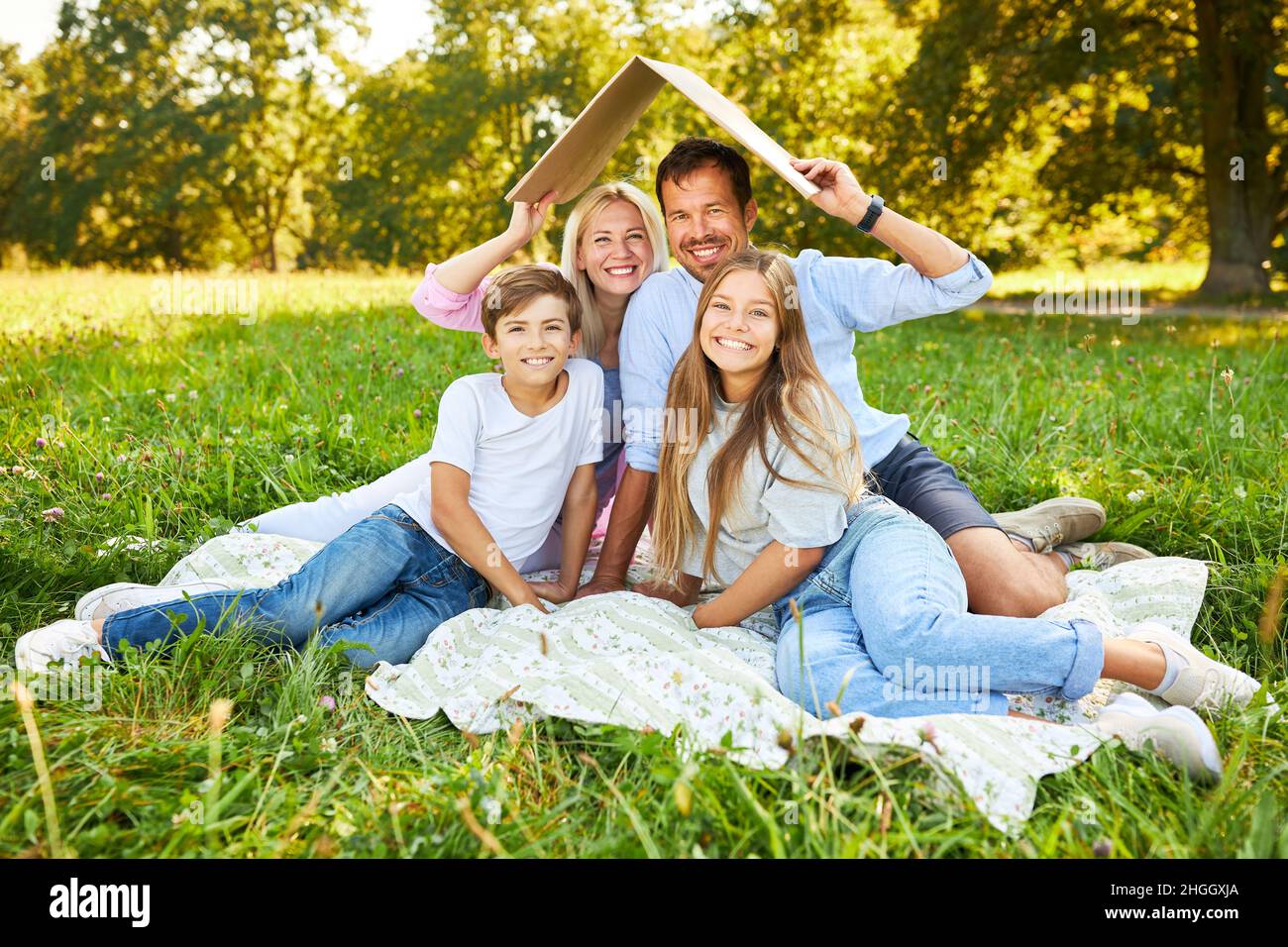 Enfants et parents avec un toit au-dessus de leur tête comme symbole pour la construction de la maison Banque D'Images