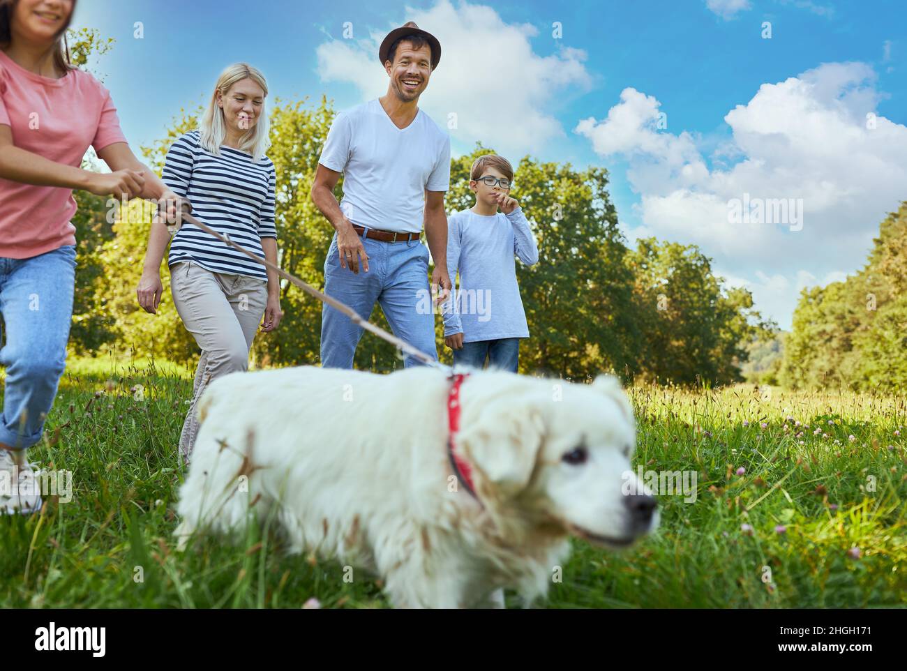 La famille et deux enfants qui marchent leur chien dans un parc en été Banque D'Images