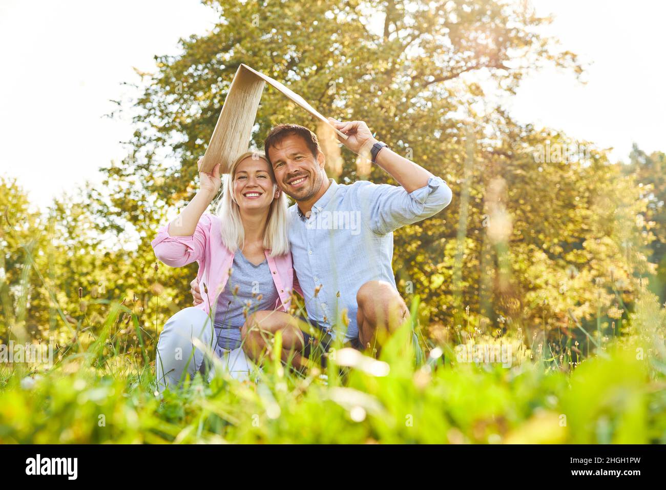 Couple heureux avec un toit au-dessus de leur tête comme symbole pour la construction de maison et la sécurité de vieillesse Banque D'Images