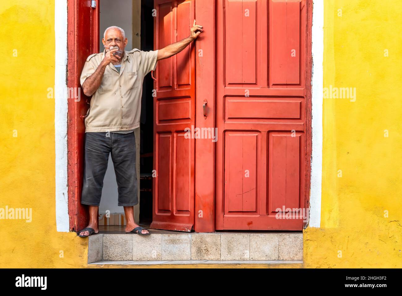 Un homme cubain fume un cigare dans la porte de sa maison de style colonial dans le centre-ville.Style de vie des personnes réelles Banque D'Images