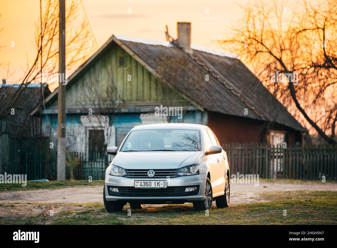 Volkswagen Polo parking sur la route de campagne sur Un arrière-plan de l'ancienne maison de village en bois traditionnelle en soirée ensoleillée Banque D'Images