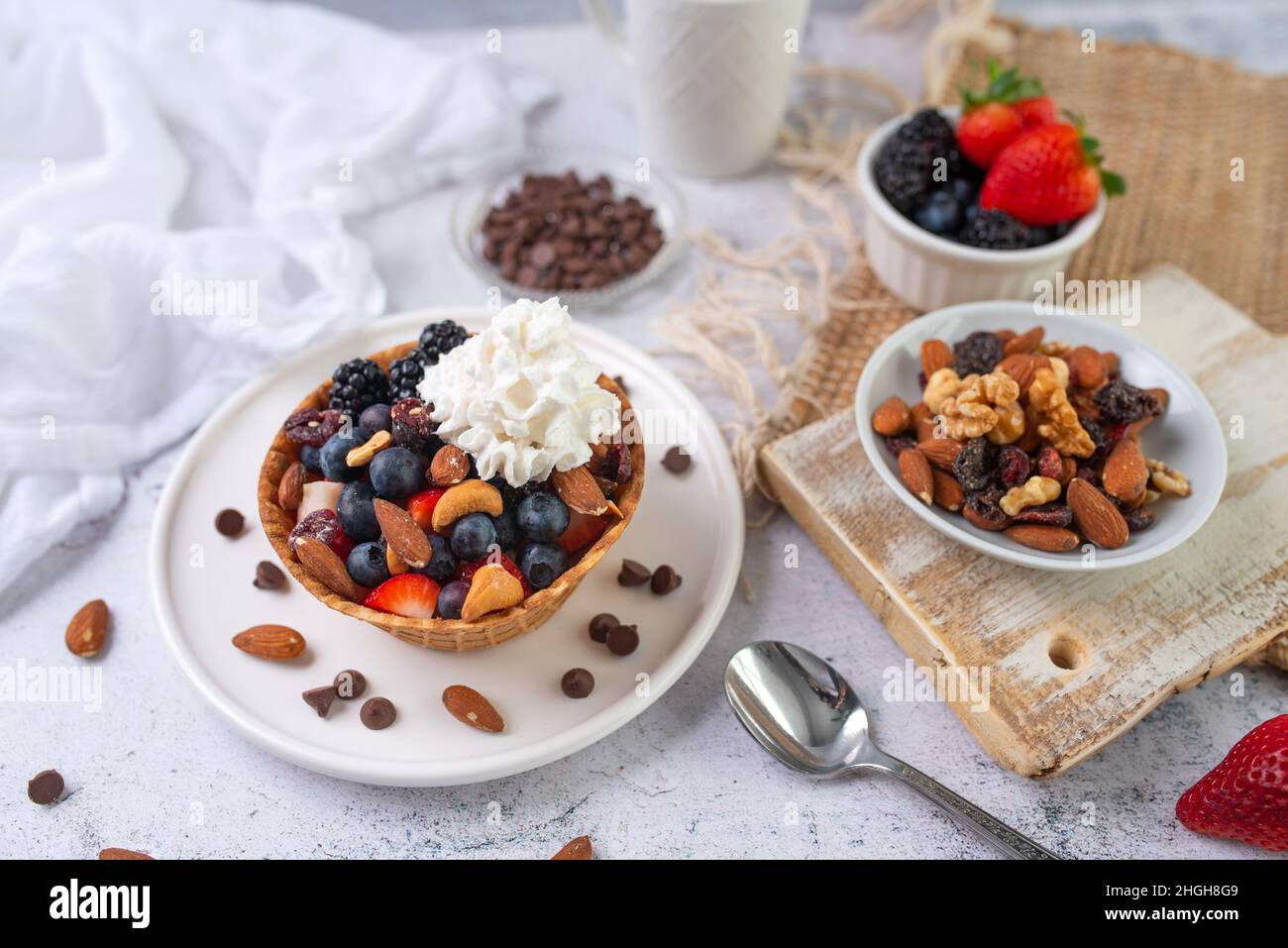 Yaourt et fruits dans un saladier.Yaourt grec dans un bol à gaufres à la crème glacée avec des fruits et des noix, dessert sain et adapté à l'alimentation.Bol à gaufres fruité. Banque D'Images