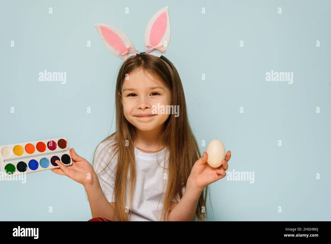 Petite fille mignonne portant des oreilles de lapin et peignant l'oeuf de pâques le dimanche matin le jour de Pâques.Copier l'espace Banque D'Images