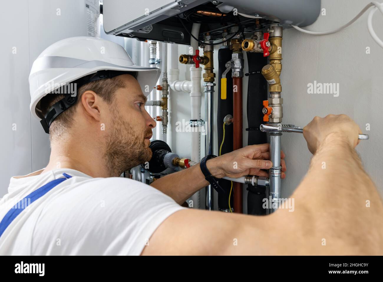 travailleur installant des tuyaux de chaudière de chauffage à gaz domestique Banque D'Images