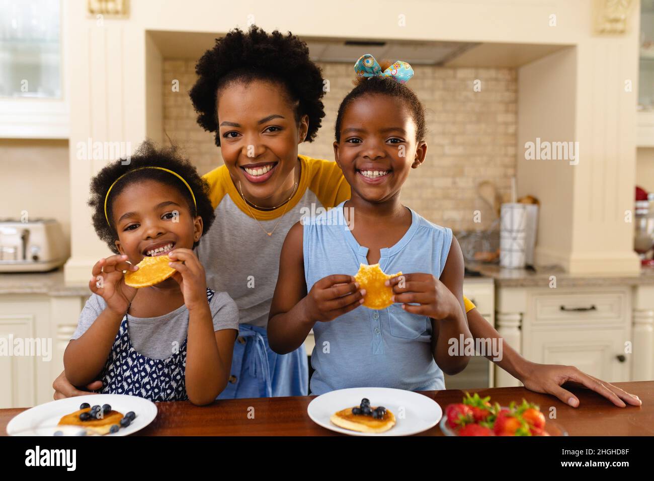 Portrait de la mère afro-américaine et de ses deux filles prenant le petit déjeuner dans la cuisine à la maison Banque D'Images