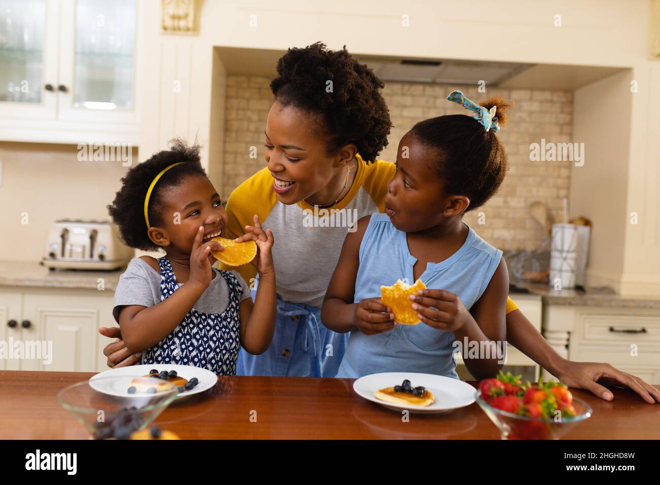Mère afro-américaine et ses deux filles prenant le petit déjeuner dans la cuisine à la maison Banque D'Images