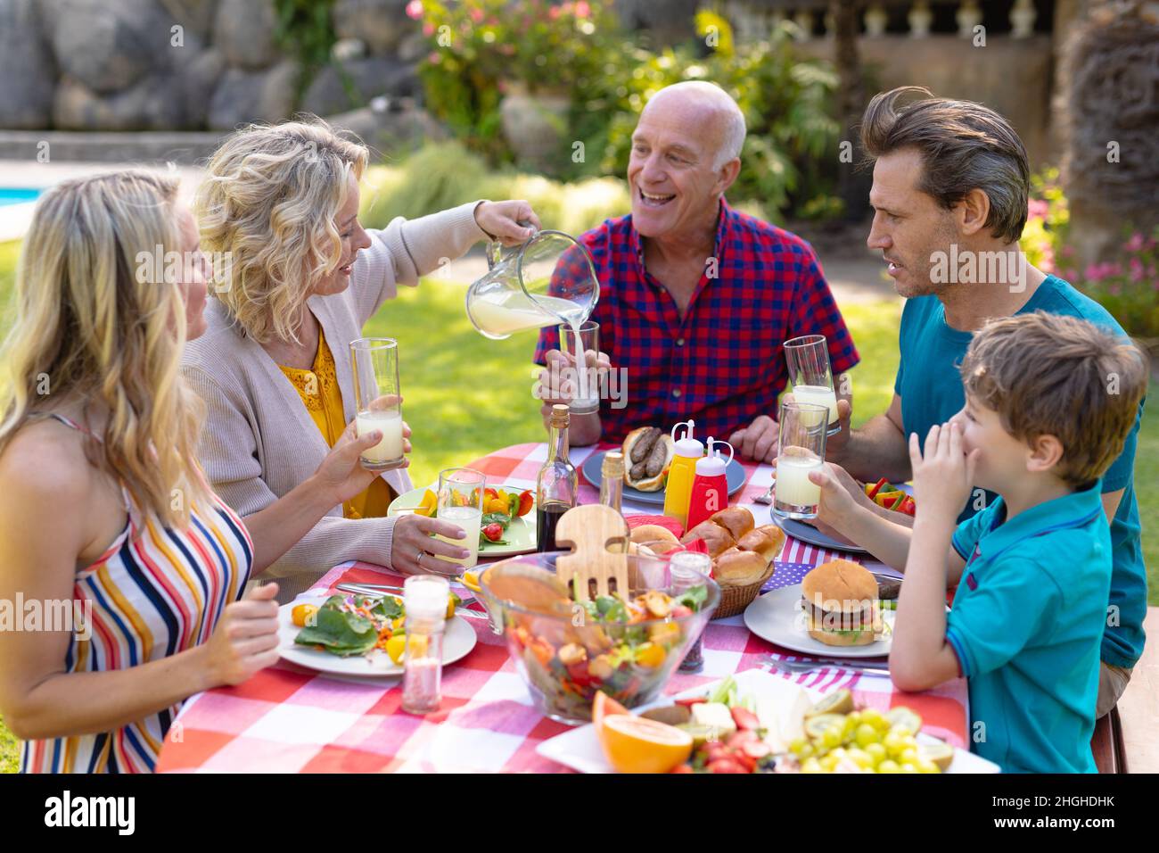 Joyeux caucasiens famille de trois générations en appréciant le déjeuner à table dans le jardin Banque D'Images