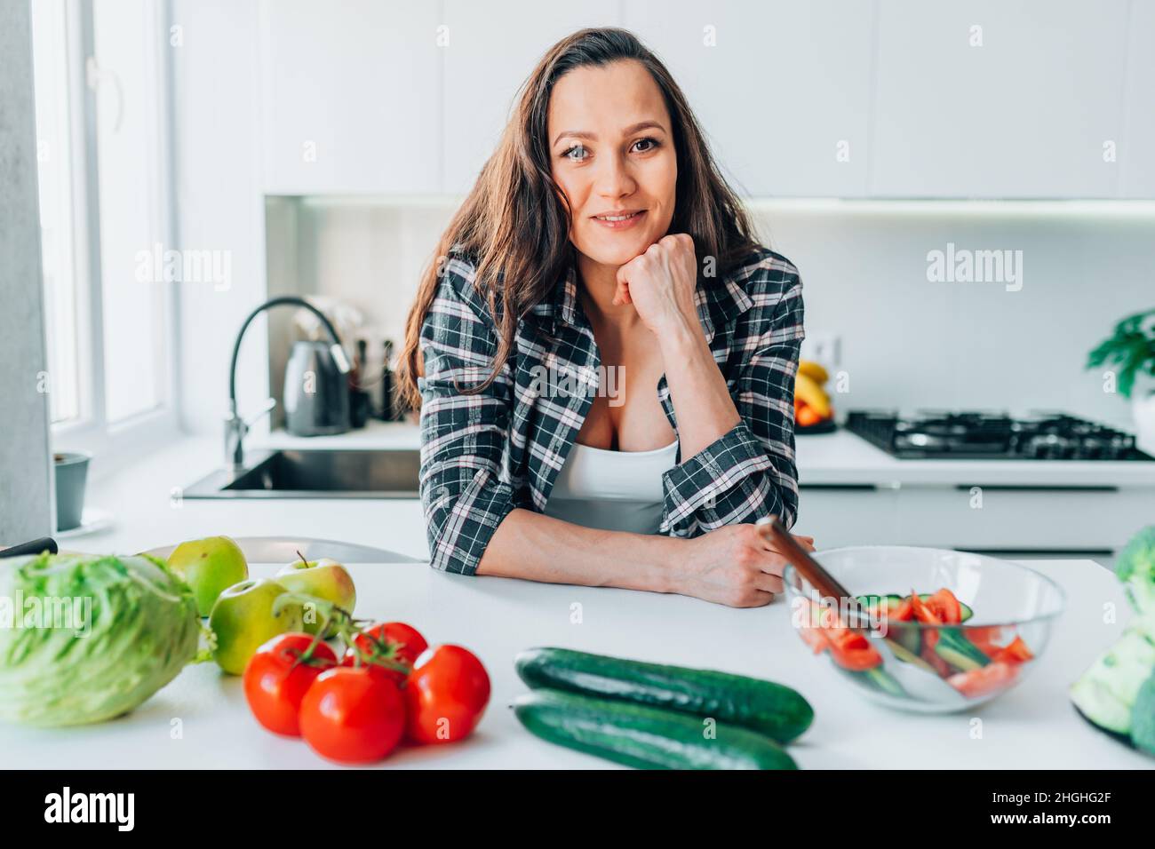 Femme enceinte préparant une salade de légumes dans une cuisine moderne et légère à la maison Banque D'Images