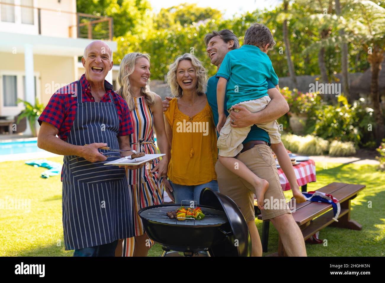 Portrait de famille caucasienne de trois générations de barbecuing ensemble dans le jardin Banque D'Images
