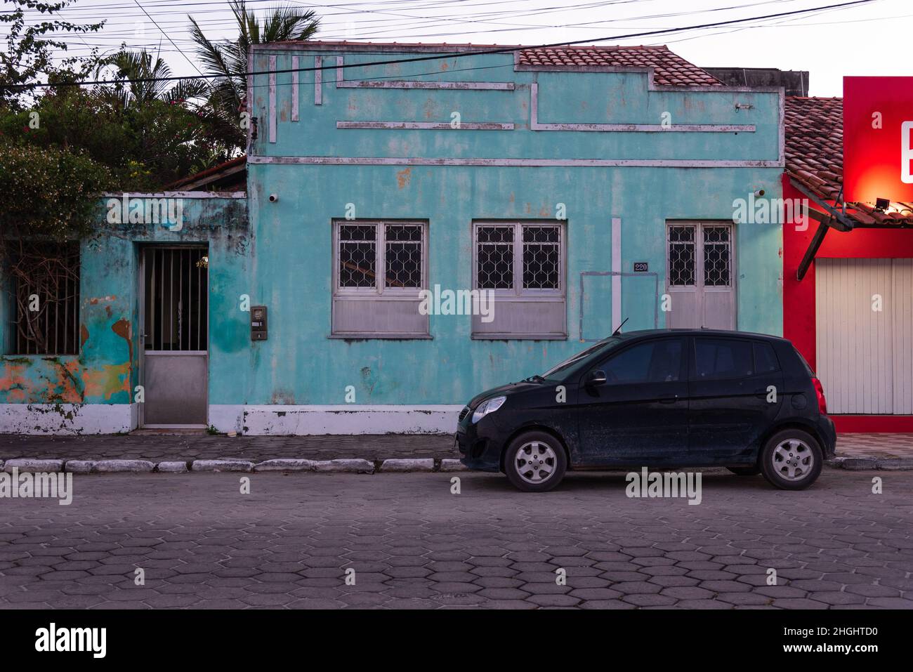 Vieille maison peinte dans la couleur sarcelle claire avec petite voiture noire garée en face au centre du Prado, Bahia, Brésil. Banque D'Images