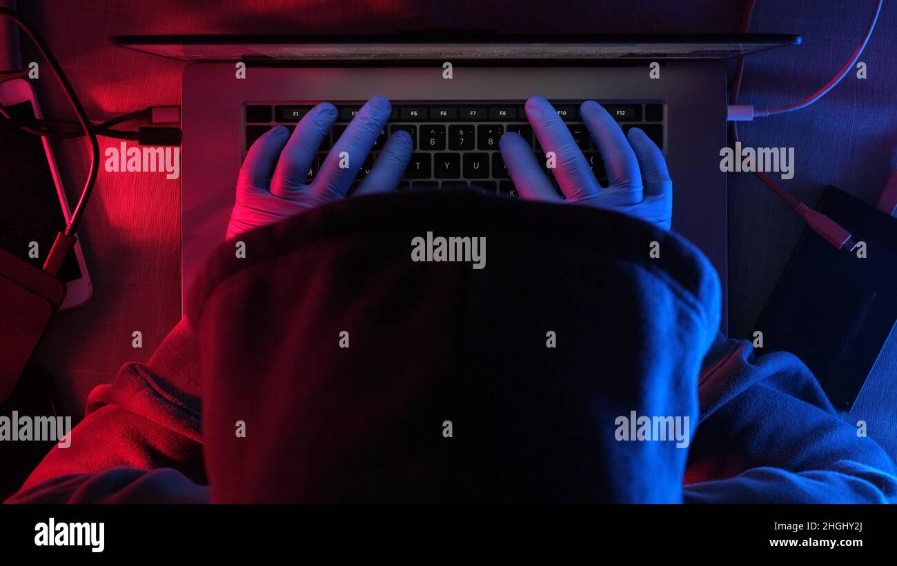 hacker travaillant sur ordinateur portable la nuit . mains d'un hacker dans des gants en caoutchouc Banque D'Images