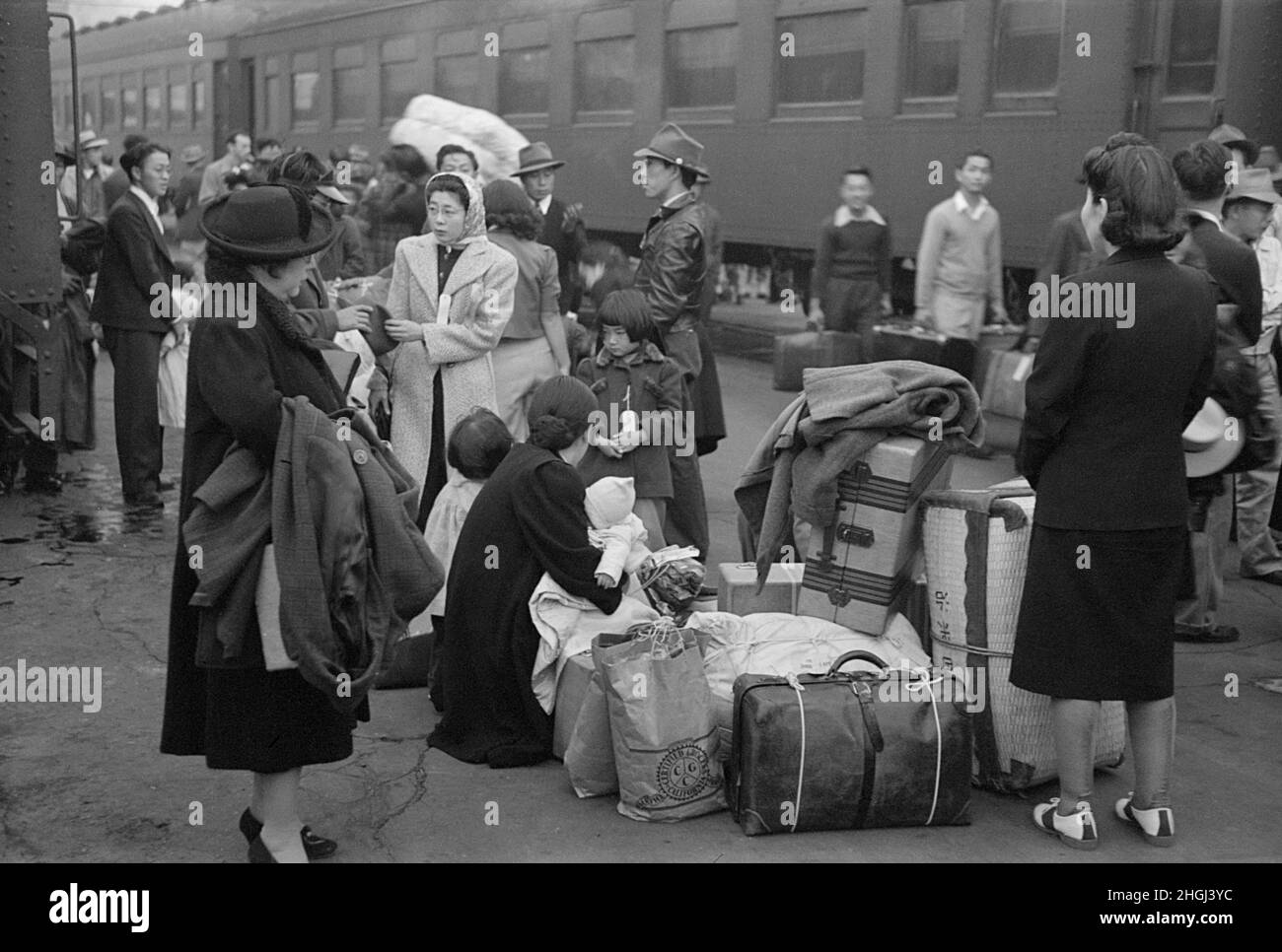 Adultes et enfants attendant avec leurs bagages pour le train pour les emmener à Owens Valley pendant l'évacuation américano-japonaise des zones de la côte ouest en vertu de l'ordre d'urgence de guerre de l'armée américaine, Los Angeles, Californie, États-Unis, Russell Lee,U.S. Office of War information/États-UnisAdministration de la sécurité agricole, avril 1942 Banque D'Images