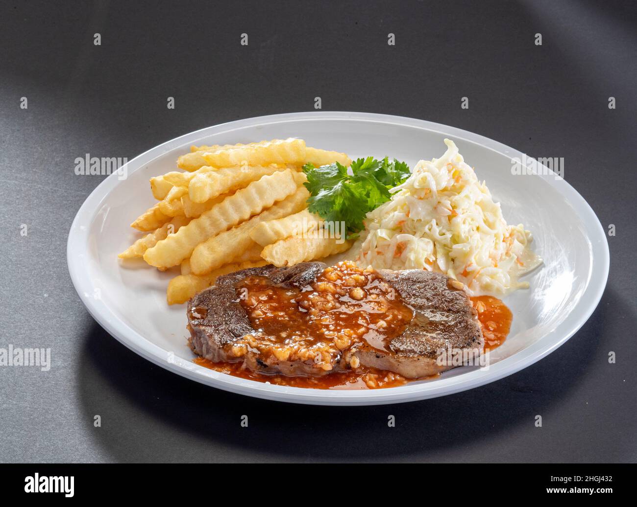 Sirloin fraîchement grillée Steak sauce avec frites et salade servi dans un plat blanc sur fond sombre Banque D'Images