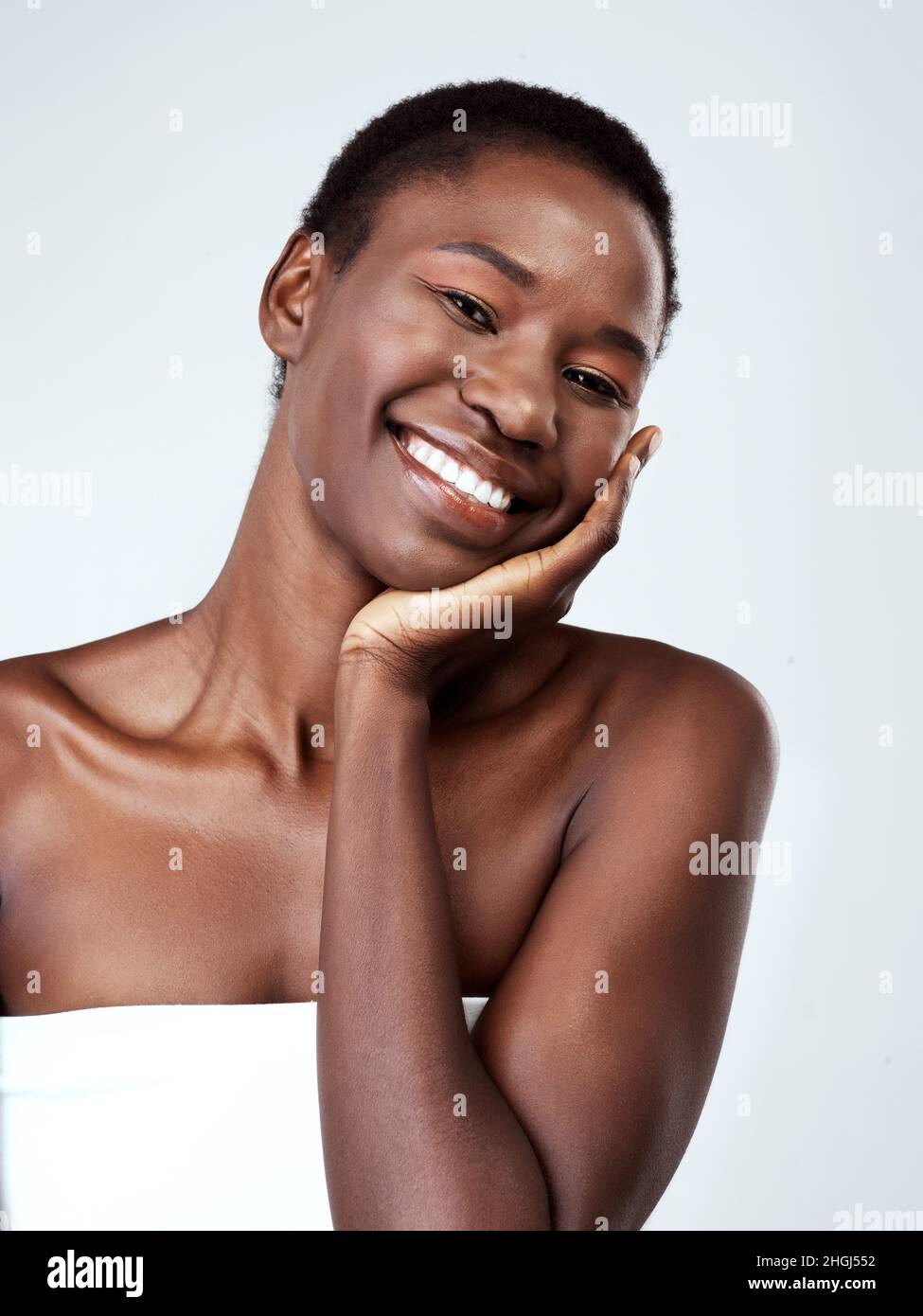 Elle a ce facteur de lueur.Portrait studio d'une belle jeune femme sentant sa peau sur fond gris. Banque D'Images