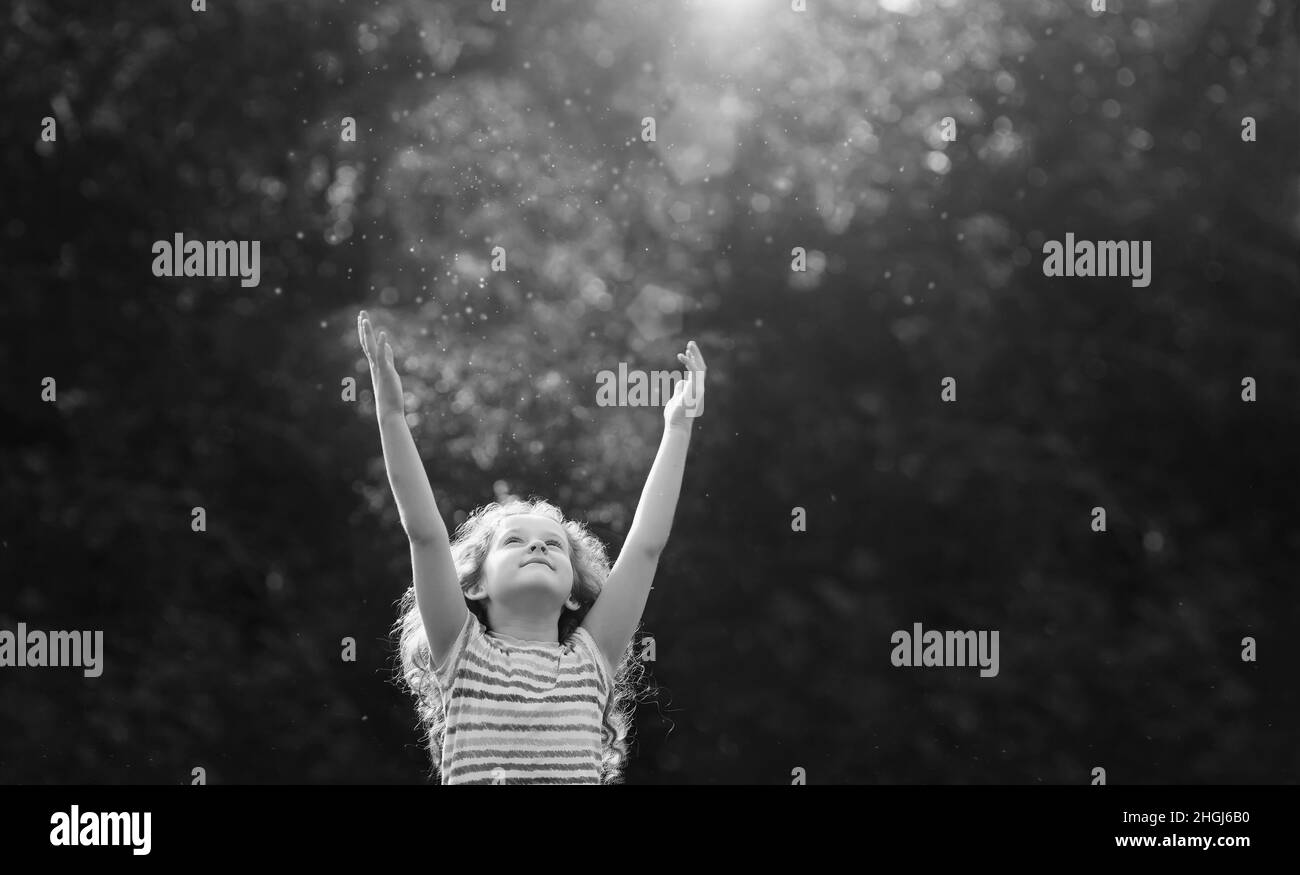 Jolie petite fille étire sa main pour attraper les rayons du soleil.Religion, don, personnes, charité, enfance heureuse,concept du monde de la paix. Banque D'Images