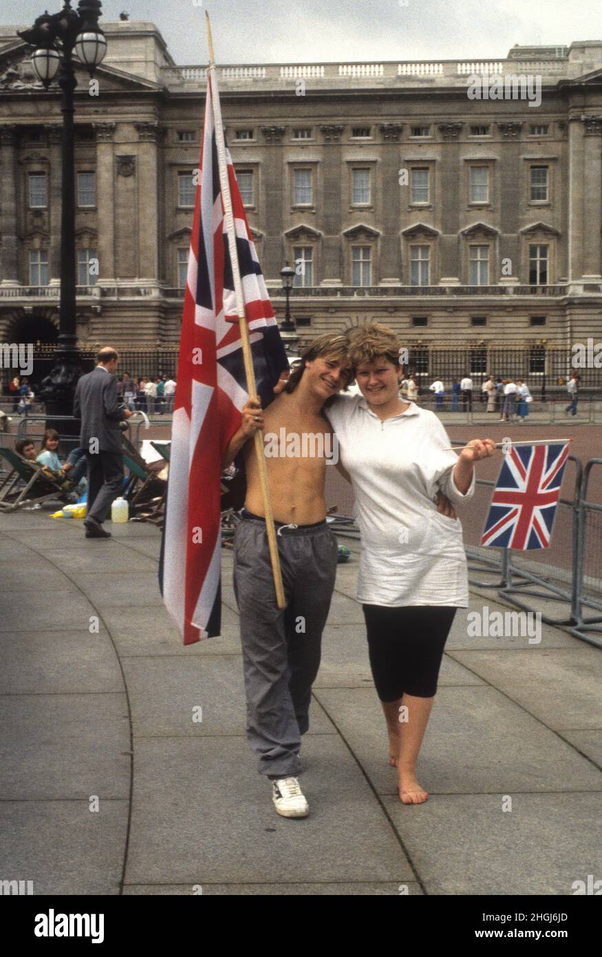 Un jeune couple est accompagné de drapeaux Union Jack tandis que les foules se rassemblent pour le mariage du Prince Andrew et de Sarah Ferguson le 23rd 1986 juillet Banque D'Images