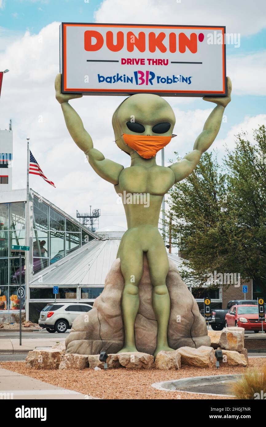 Une statue extraterrestre contient un panneau Dunkin' Donuts à Roswell, au Nouveau-Mexique, tout en portant une couverture de visage en tant que symbole de Covid-19 et de masques Banque D'Images