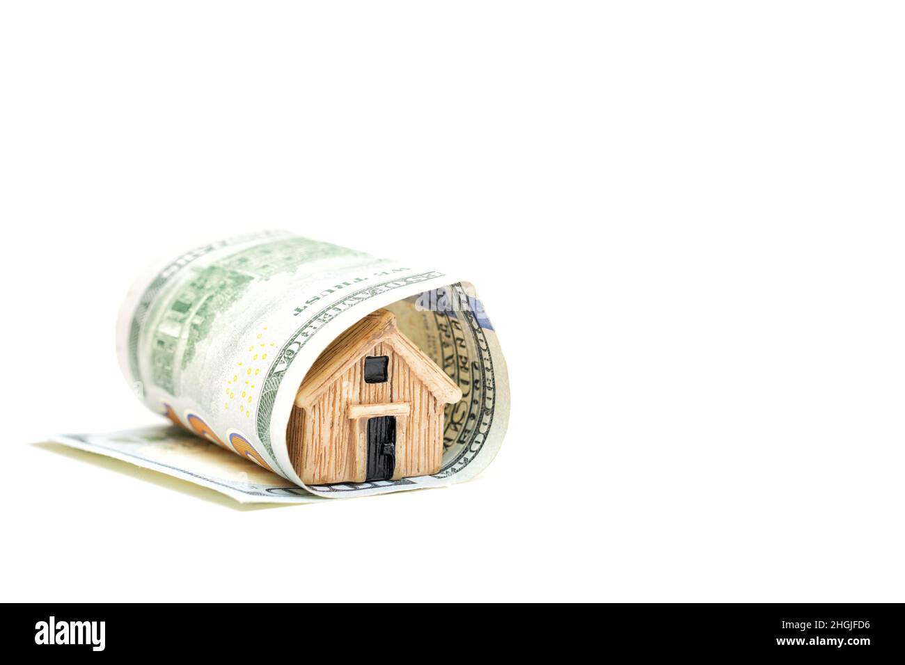 Modèle de maison miniature enveloppé dans une facture de cent dollars isolée sur fond blanc.Concept d'assurance de biens résidentiels. Banque D'Images