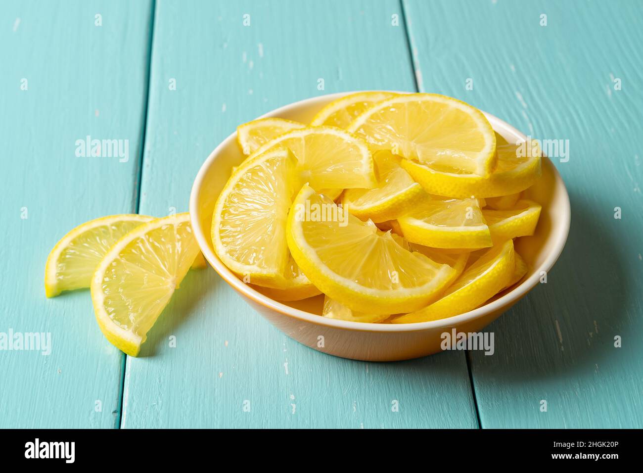 Gros plan de citron juteux frais dans un bol sur une table en bois turquoise.Tranches de citron jaune brut pour antioxydant, saine alimentation, vitamine C concept Banque D'Images