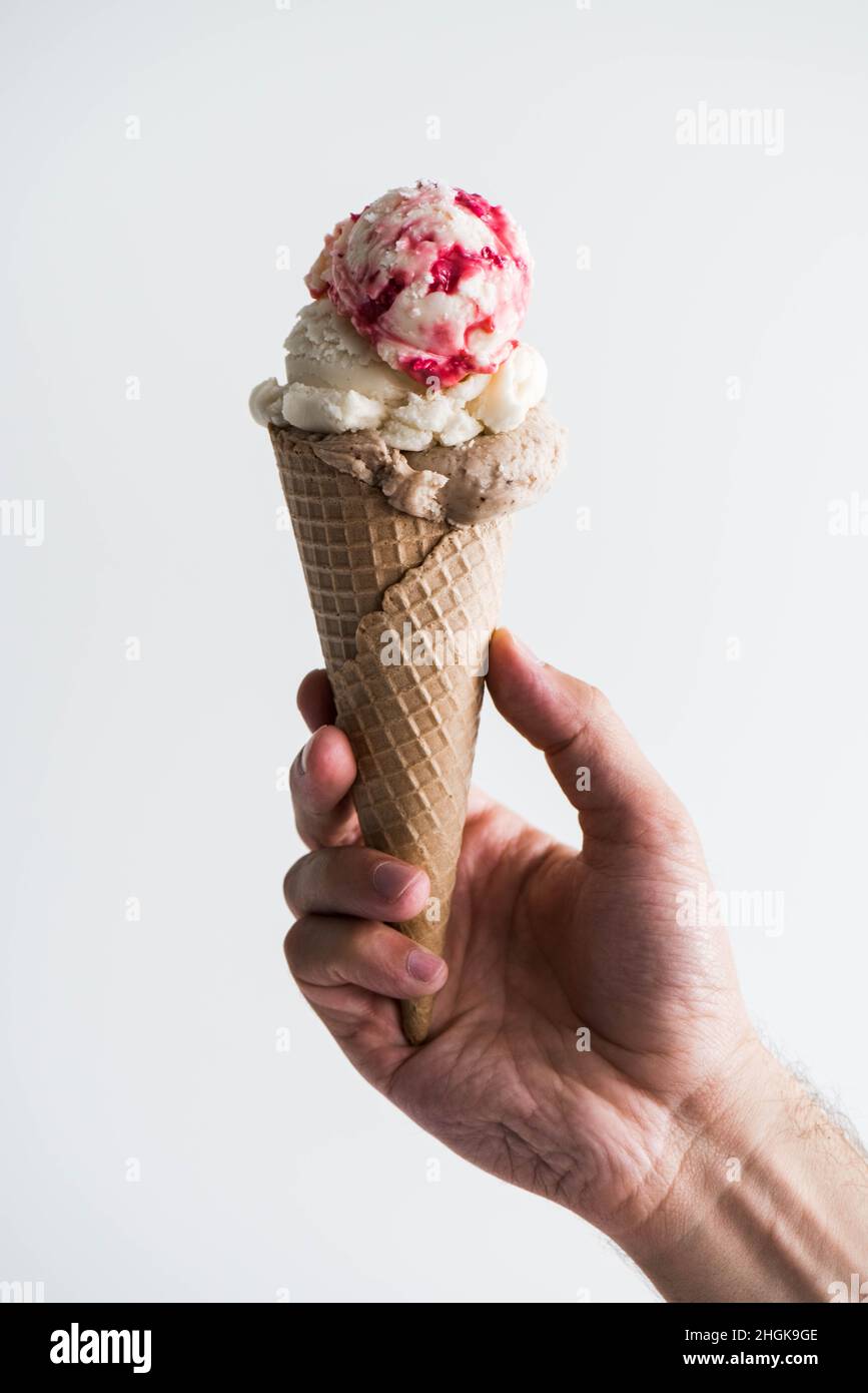Crème glacée sur la main masculine.Homme tenant le cornet de gaufres avec de la crème glacée sur fond blanc. Banque D'Images