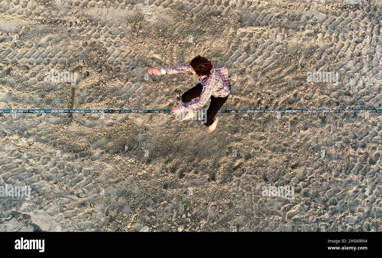 Vue aérienne au-dessus de l'homme en train de desserrer l'équilibrage sur la corde et de faire des acrobaties, démontrant l'agilité, Pacific Beach à San Diego, Californie, États-Unis Banque D'Images