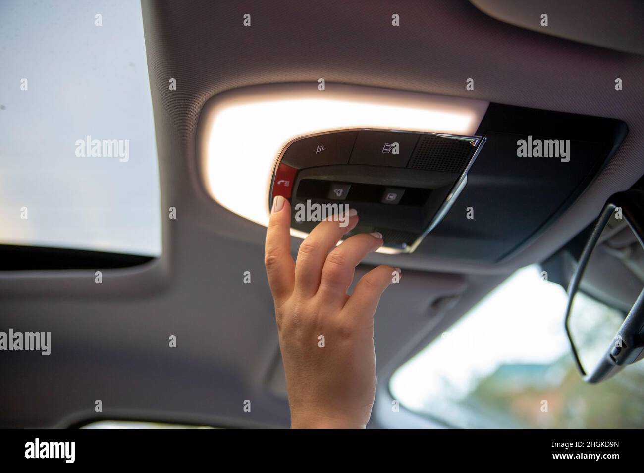 appuyez à la main sur le bouton sos de la console de plafond dans la voiture moderne Banque D'Images