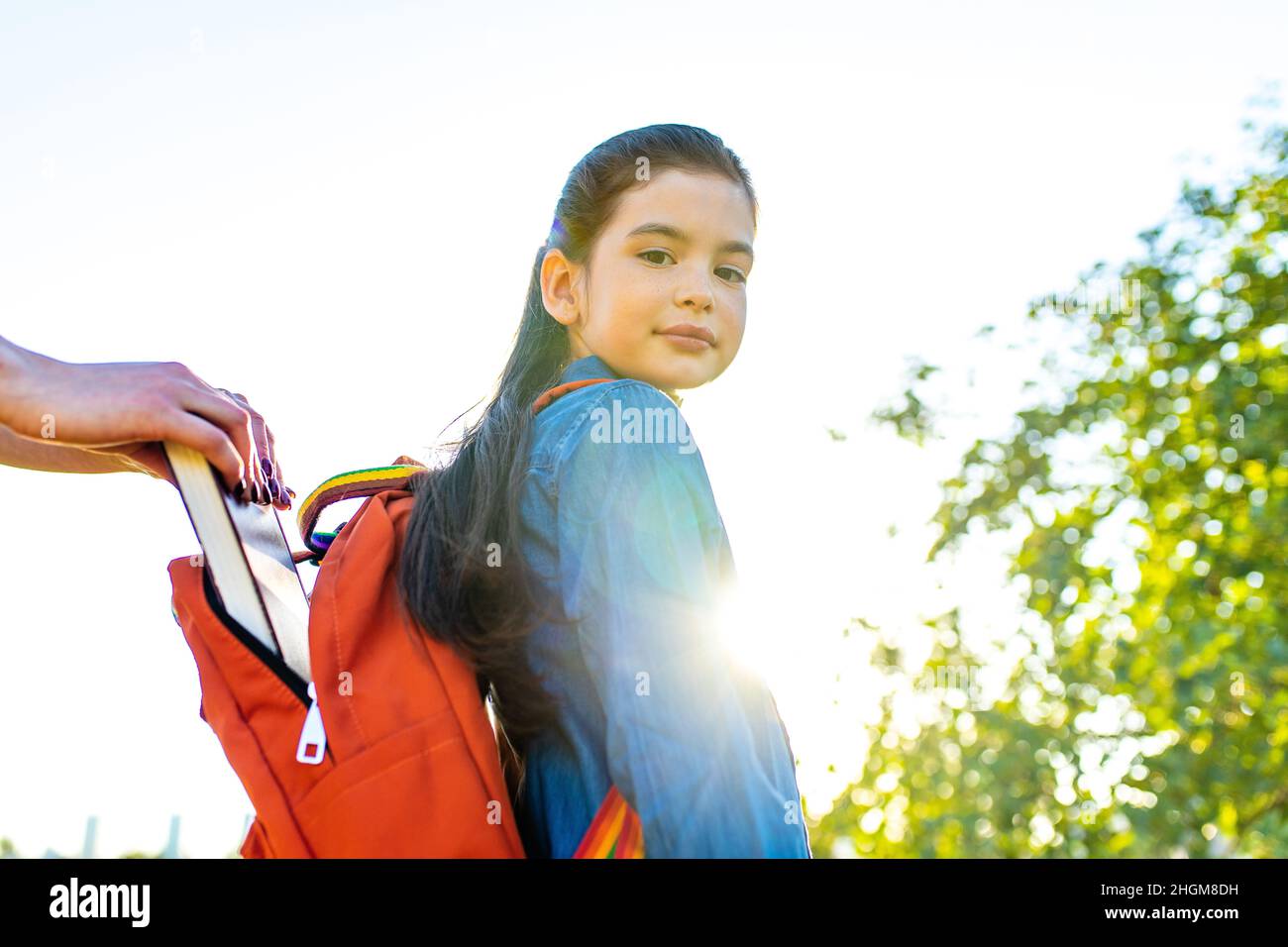 Jeune fille indienne souriante portant un sac à dos d'école et un t-shirt bleu dans le parc Banque D'Images