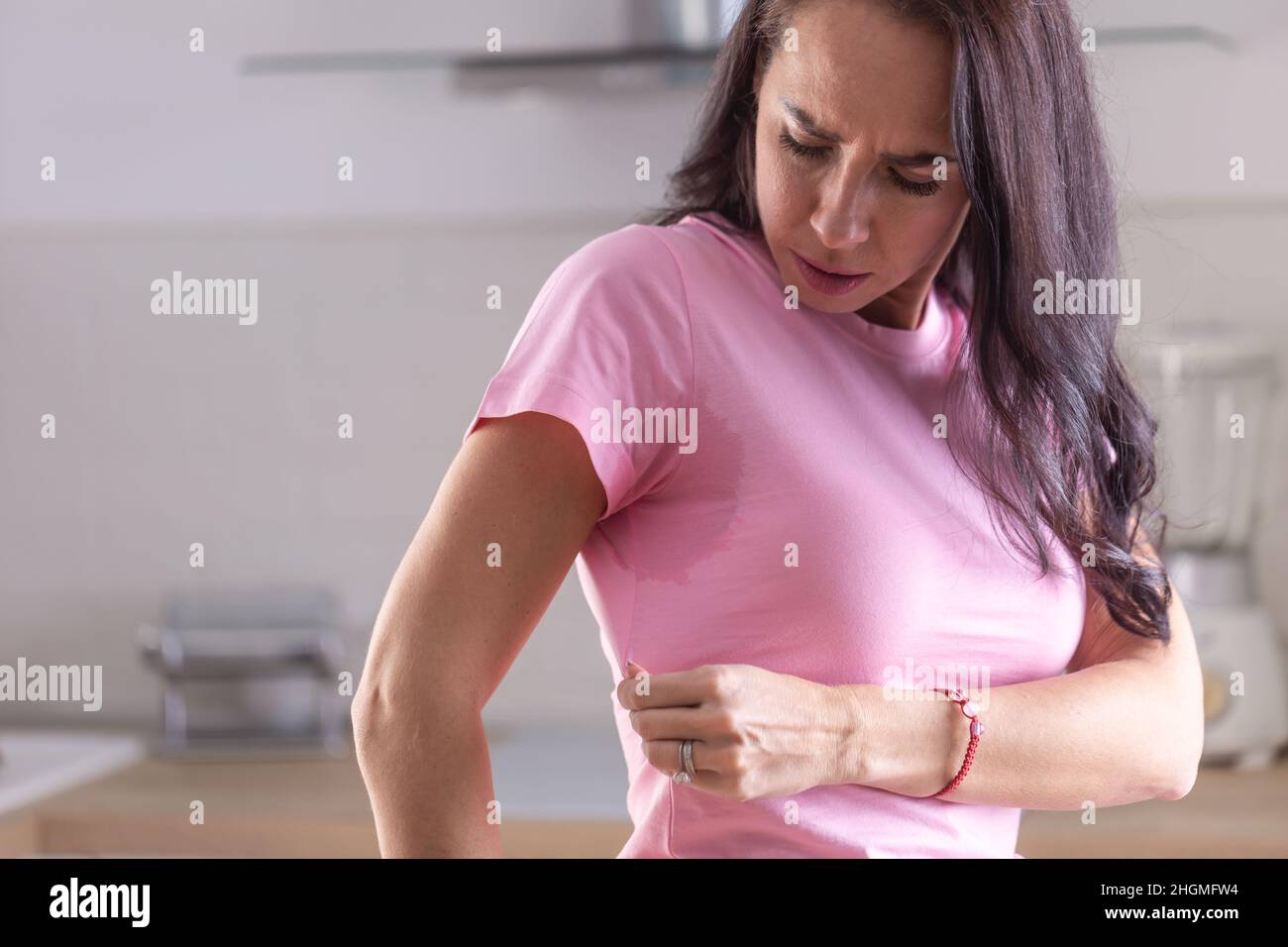 Transpiration excessive visible par des taches sur une chemise rose d'une jeune femme. Banque D'Images