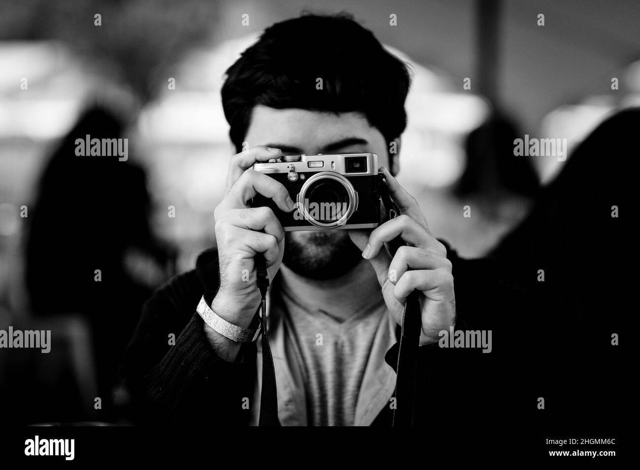Homme aux cheveux sombres prenant une photo avec un appareil photo vintage Banque D'Images